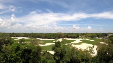 Meksika 'da kum sığınakları ve tropikal bitki örtüsü olan bir golf sahasının panoramik hava görüntüsü. Çekim 4K