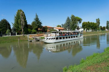 Son durağı İtalya 'daki Venedik Gölü olan bir tur sırasında Brenta Nehri' nde bir çok yolcuyla birlikte seyahat eden bir turist teknesi.