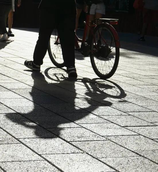 Silhueta Uma Pessoa Bicicleta Lançando Longas Sombras Uma Rua Ladrilhada Imagens Royalty-Free