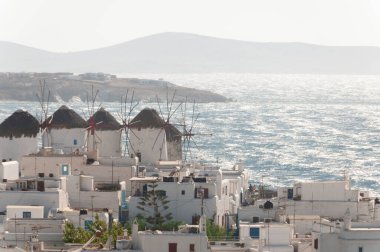 Panoramic view from above of Mykonos island's famous mills and old town, in the background the windswept sea in Greece