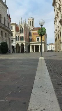 Padua 'daki tarihi merkezin dikey zaman atlaması, arka planda ünlü Pedrocchi kahvesi ve güneşli bir günde yürüyen insanlar.