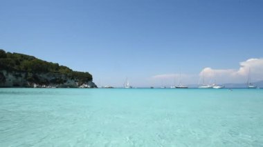 Yunanistan 'ın Antipaxos adasının sahildeki körfezinin HD videosu. Gemiler berrak bir gökyüzünün altında kristal berrak bir denize demirlemişti. Seyahat, rahatlama ve doğa aşıkları için mükemmel bir yer.