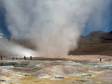 People run for cover as a sudden small twister winds its way through southern Bolivia's Sol de Manana Geysers and Geothermal area. This remote location is often visited by tourists taking an extended trek across Bolivia's Altiplano and salt flats