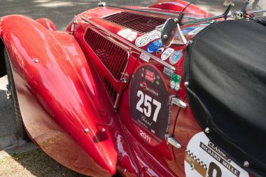 1939 yılından kırmızı bir Alfa Romeo 6C 2500 Super Sport Corsa otomobili. Ön taraf, kaput manzarası ve çamurluk. Açık hava, güneş ışığı. 