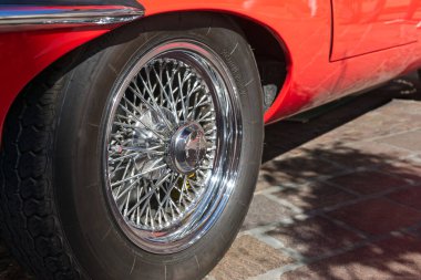 1969 'dan kalma üstü açık kırmızı bir Jaguar E-Type' ın lastik ve tekerleklerine yakın çekim..