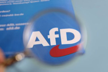 Alternatif Almanya siyasi partisi anlamına gelen bir broşürde AfD harflerini büyüten bir büyüteç. Haziran 2024 'te Almanya' da komünist ve Avrupa seçimleri.