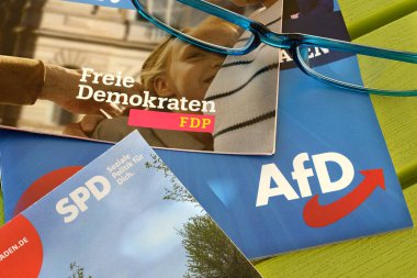 2024 Avrupa seçimleri Almanya 'da. SPD, FDP ve AFD gibi Alman siyasi partilerinin kampanya broşürleri. El ilanlarına yerleştirilmiş okuma gözlükleri.