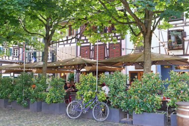 Fransa 'nın Strazburg kentindeki Place du Marche Gayot' taki bitkilerin arkasına gizlenmiş restoranlar. Arka planda yarı keresteli Alsas evleri.