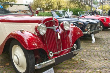 Adler Trumpf Junior Karmann otomobili 1937 'de Baden-Baden Classics 2024, Almanya' da ortaya çıktı. Arka planda diğer klasik arabalar.