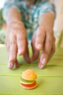 Eller yeşil bir masada mini bir hamburger kapmak istiyor. Fast food aşermesi ve diyet konsepti.