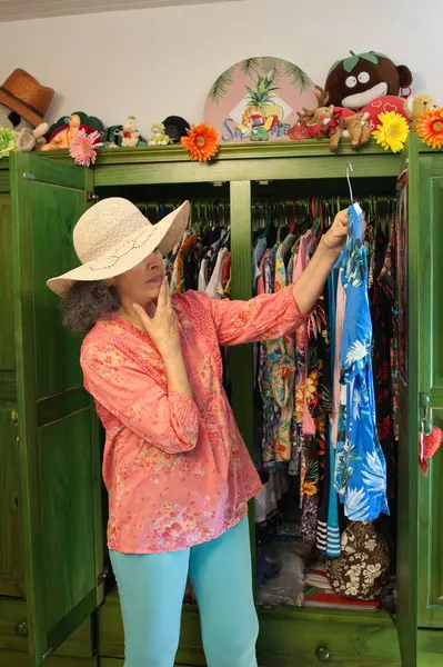 Açık bir gardırobun önündeki kadın. O, bir Hawaii gömleği üzerinde karar veriyor. Plaj tatili hazırlığı. 