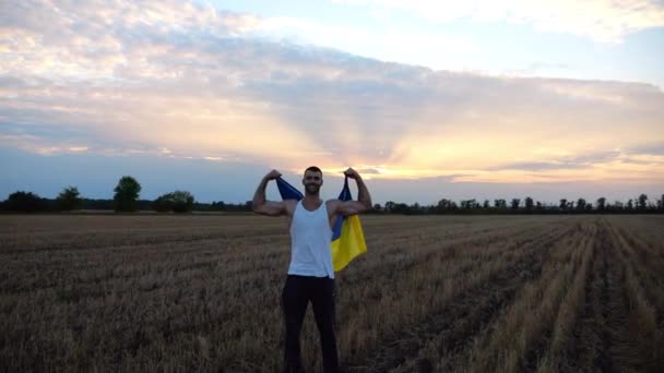 Ukraiński Sportowiec Stoi Łące Jęczmiennej Pokazując Bicepsy Chorągwią Narodową Rękach — Wideo stockowe