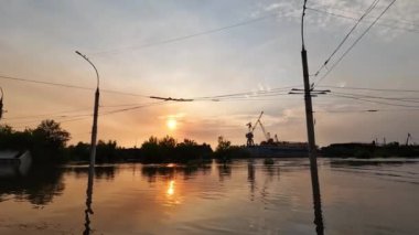 Kherson kasabasındaki sokakları su basmıştı. Arka planda güzel bir günbatımı vardı. Novaya Kakhovka kentindeki Dnipro nehrinde baraj patlaması. Kakhovka Hidroelektrik Santralinin patlamasının sonuçları