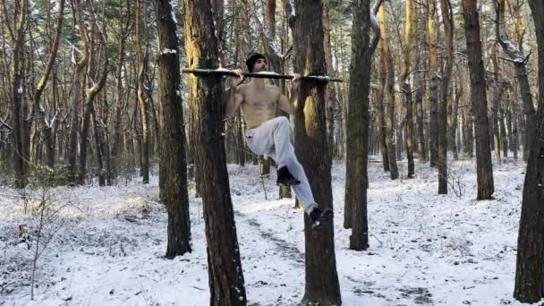 运动员在森林的横杆上做静态运动 一个体格结实的人在室外训练腹部 年轻的运动员在冬天锻炼 体育概念和积极的生活方式 慢一点 — 图库视频影像