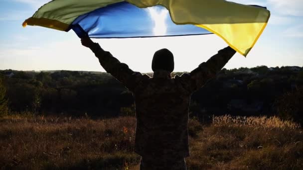 Militar Uniforme Ergue Sobre Cabeça Bandeira Ucraniana Contra Luz Solar — Vídeo de Stock
