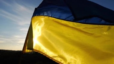 Güneş ışığının arka planında rüzgarda dalgalanan Ukrayna bayrağı. Ukrayna 'nın mavi-sarı sembolü. Kırsalda güneş parıldıyor. Rus saldırısına karşı barış ve destek kavramı.