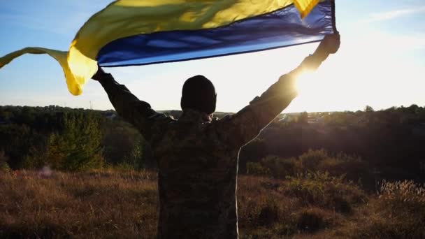 Üniformalı Asker Arka Planda Güneş Işığına Karşı Ukrayna Bayrağıyla Ayakta — Stok video