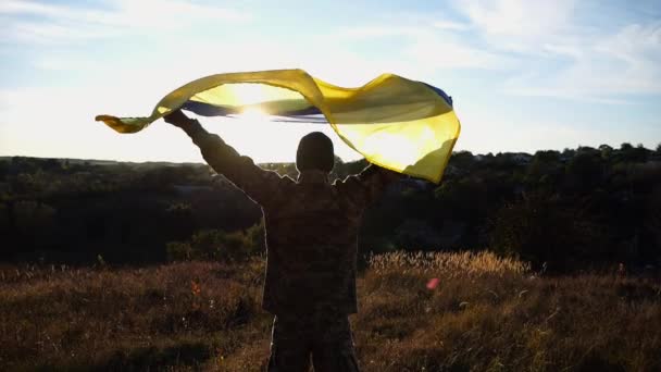 身着制服的军人头顶高举乌克兰国旗 背对阳光 为纪念战胜俄国侵略而高举国旗的乌克兰男兵 — 图库视频影像