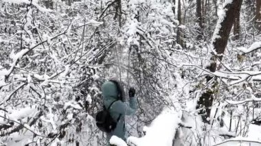 Ormandaki bir daldan kar sallayan mutlu kadın. Ormandaki genç kızı kar kaplıyor. Gülümseyen neşeli bayan eğleniyor ve kış tatilinin tadını çıkarıyor. Kış tatili kavramı. Yavaşla.