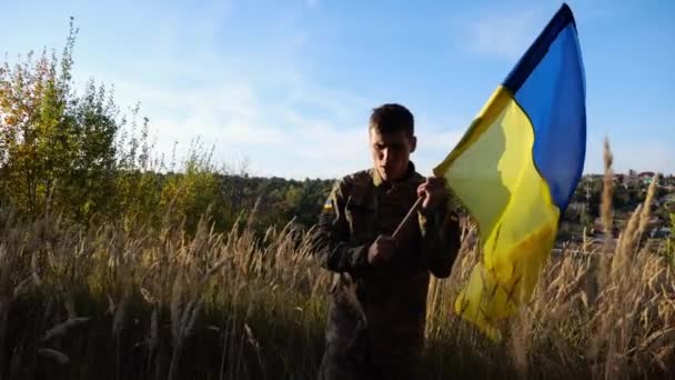 Νεαρός Στρατιωτικός Στολή Περπατάει Κυματιστή Σημαία Της Ουκρανίας Στην Ύπαιθρο — Αρχείο Βίντεο