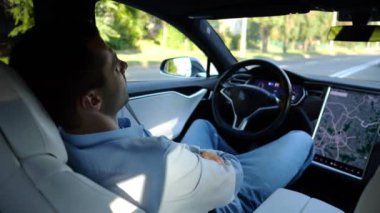 Kentsel yolda kendi kendini kullanan bir erkek işadamı deneyimi. Şehirdeki otomatik pilotla elektrikli otomobilde dinlenen kendine güvenen bir iş adamı. Yavaş çekim