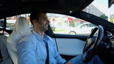 Kentsel yolda kendi kendini kullanan bir erkek işadamı deneyimi. Şehirdeki otomatik pilotla elektrikli otomobilde dinlenen kendine güvenen bir iş adamı. Yavaş çekim
