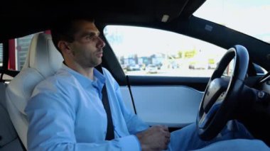 Kentsel yolda kendi kendini kullanan bir erkek işadamı deneyimi. Şehirdeki otomatik pilotla elektrikli otomobilde dinlenen kendine güvenen bir iş adamı. Yavaş çekim