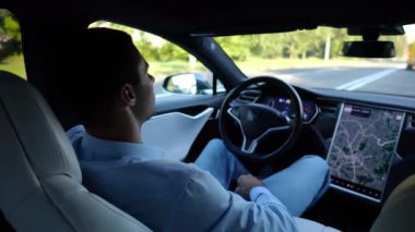 Kentsel yolda kendi kendini kullanan bir erkek işadamı deneyimi. Şehirdeki otomatik pilotla elektrikli otomobilde dinlenen kendine güvenen bir iş adamı. Yavaş çekim