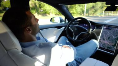 Kentsel yolda kendi kendini kullanan bir erkek işadamı deneyimi. Şehirdeki otomatik pilotla elektrikli otomobilde dinlenen kendine güvenen bir iş adamı. Yavaş çekim