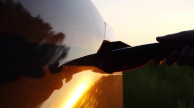 Elektrikli arabaya şarj aleti takan bir kadın el. Genç bir kadın elektrikli otomobili şarj istasyonuna bağlıyor. Kız EV otomobiline güç bağlantısı yerleştiriyor. Çevre dostu ulaşım kavramı.