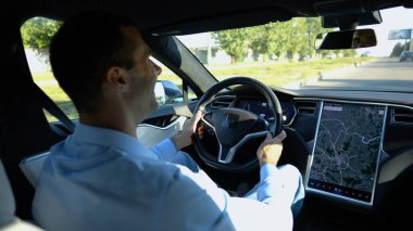 Başarılı bir iş adamı şehirde elektrikli araçla dolaşıyor. Kentsel yolda modern elektrikli araba kullanan bir erkek girişimci. Güneşli bir günde otomotiv işi yapan bir iş adamı. İşe gidip gelen genç adam..