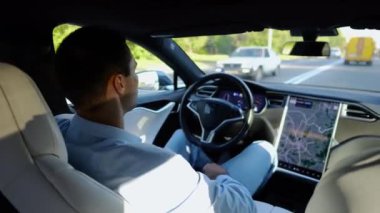 Kentsel yolda kendi kendini kullanan bir erkek işadamı deneyimi. Şehirdeki otomatik pilotla elektrikli otomobilde dinlenen kendine güvenen bir iş adamı. Yavaş çekim