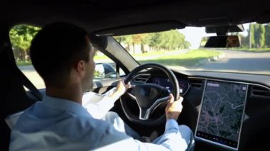 Başarılı bir iş adamı şehirde elektrikli araçla dolaşıyor. Kentsel yolda modern elektrikli araba kullanan bir erkek girişimci. Güneşli bir günde otomotiv işi yapan bir iş adamı. İşe gidip gelen genç adam..