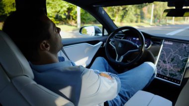 Kentsel yolda kendi kendini kullanan bir erkek işadamı deneyimi. Şehirdeki otomatik pilotla elektrikli otomobilde dinlenen kendine güvenen bir iş adamı. Yavaş çekim