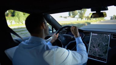 Başarılı girişimci kentsel yolda elektrikli araç sürerken iyi haberler aldı. Şehirdeki elektrikli araçla gezerken başarıları kutlayan genç ve mutlu bir işadamı. Yavaş çekim