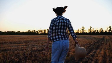 Gün batımında arpa tarlasında koşan kadın çiftçi. Agronomist gün batımında buğday çayırlarında koşuyor. Güzel manzara manzarası. Tarım sektörü kavramı. Yavaşla.