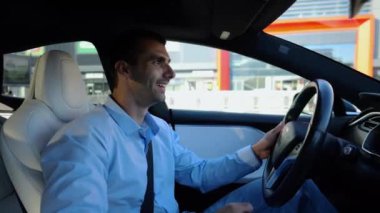 Kentsel yolda kendi kendini kullanan bir erkek işadamı deneyimi. Şehirdeki otomatik pilotla elektrikli otomobilde dinlenen kendine güvenen bir iş adamı. Yavaş çekim