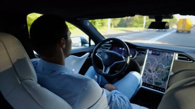 Kentsel yolda kendi kendini kullanan bir erkek işadamı deneyimi. Şehirdeki otomatik pilotla elektrikli otomobilde dinlenen kendine güvenen bir iş adamı. Yavaş çekim