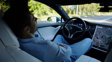 Kentsel yolda kendi kendini kullanan bir erkek işadamı deneyimi. Şehirdeki otomatik pilotla elektrikli otomobilde dinlenen kendine güvenen bir iş adamı. Yavaş çekim