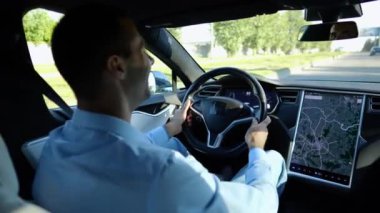 Başarılı bir iş adamı şehirde elektrikli araçla dolaşıyor. Kentsel yolda modern elektrikli araba kullanan bir erkek girişimci. Güneşli bir günde otomotiv işi yapan bir iş adamı. İşe gidip gelen genç adam..