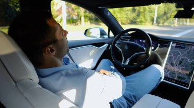 Kentsel yolda kendi kendini kullanan bir erkek işadamı deneyimi. Şehirdeki otomatik pilotla elektrikli otomobilde dinlenen kendine güvenen bir iş adamı. Yavaş çekim