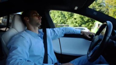 Kentsel yolda kendi kendini kullanan bir erkek işadamı deneyimi. Şehirdeki otomatik pilotla elektrikli otomobilde dinlenen kendine güvenen bir iş adamı. Yavaş çekim