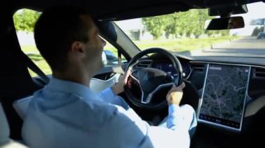 Başarılı bir iş adamı şehirde elektrikli araçla dolaşıyor. Kentsel yolda modern elektrikli araba kullanan bir erkek girişimci. Güneşli bir günde otomotiv işi yapan bir iş adamı. İşe gidip gelen genç adam..
