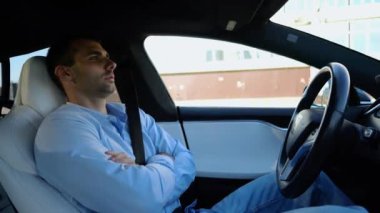 Kentsel yolda kendi kendini kullanan bir erkek işadamı deneyimi. Şehirdeki otomatik pilotla elektrikli otomobilde dinlenen kendine güvenen bir iş adamı. Yavaş çekim