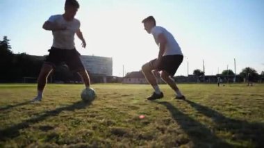 Gün batımında stadyumda oynayan iki sporcu. Profesyonel futbolcular yeşil sahada topla oyunlar oynuyorlar. Genç adamlar Meadow 'da antrenman yapıyor. Serbest stil futbol kavramı. Yavaş çekim