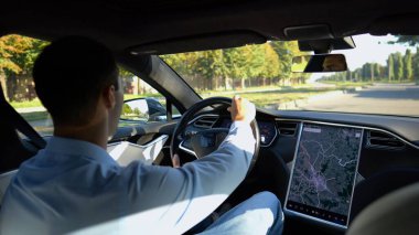 Başarılı bir iş adamı şehirde elektrikli araçla dolaşıyor. Kentsel yolda modern elektrikli araba kullanan bir erkek girişimci. Güneşli bir günde otomotiv işi yapan bir iş adamı. İşe gidip gelen genç adam..