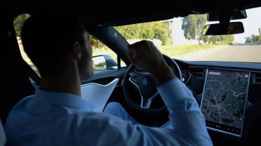 Başarılı girişimci kentsel yolda elektrikli araç sürerken iyi haberler aldı. Şehirdeki elektrikli araçla gezerken başarıları kutlayan genç ve mutlu bir işadamı. Yavaş çekim