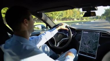 Başarılı bir iş adamı şehirde elektrikli araçla dolaşıyor. Kentsel yolda modern elektrikli araba kullanan bir erkek girişimci. Güneşli bir günde otomotiv işi yapan bir iş adamı. İşe gidip gelen genç adam..