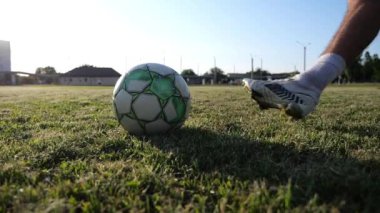 Erkek futbolcu gün batımında stadyumda penaltı atışı yapıyor. Yeşil sahada topa vuran sporcu bacağı. Genç adam Meadow 'da eğitim görüyor. Serbest stil futbol kavramı. Yavaş