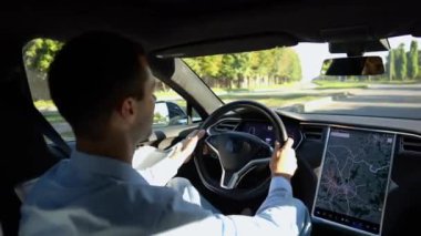 Başarılı bir iş adamı şehirde elektrikli araçla dolaşıyor. Kentsel yolda modern elektrikli araba kullanan bir erkek girişimci. Güneşli bir günde otomotiv işi yapan bir iş adamı. İşe gidip gelen genç adam..